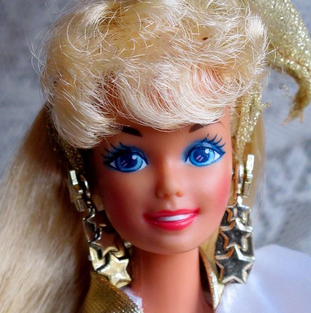 the face of a 1980s Barbie with smoky blue eyeshadow, chunky gold star earrings, and blonde hair with voluminous bangs